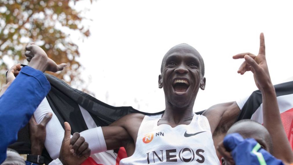 ATHLETICS-MARATHON-AUSTRIA-KENYA Кениец Элиуд Кипчоге (в белой майка) ликует, поле преодоления финишной черты мифического двухчасового барьера в марафоне 12 октября 2019 года в Вене. (Фото ALEX HALADA / AFP через Getty Images)